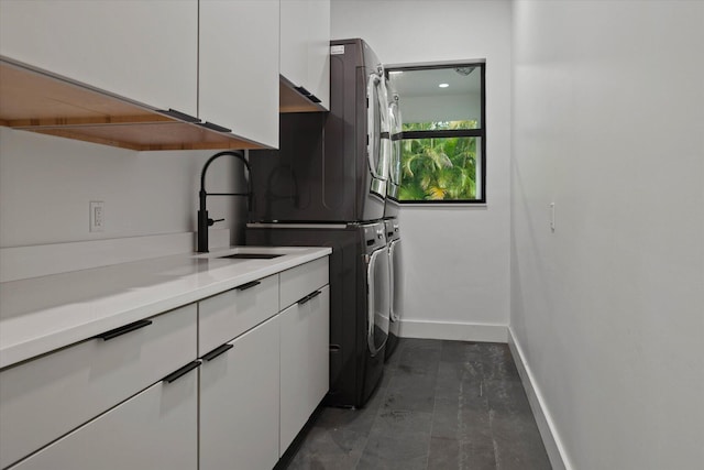 laundry room with cabinets, sink, and stacked washer / dryer