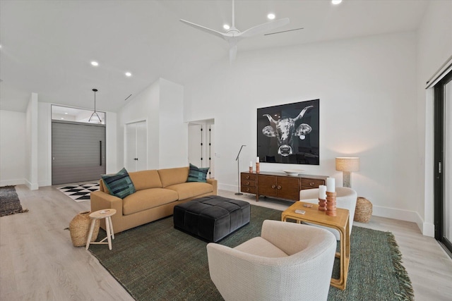 living room featuring high vaulted ceiling, ceiling fan, and light wood-type flooring