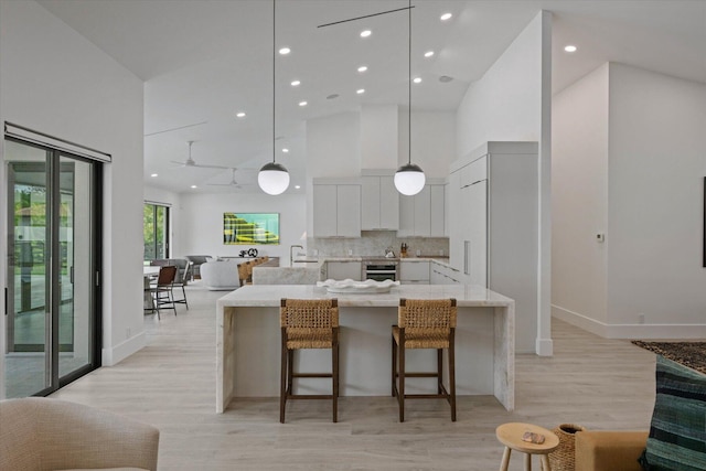 kitchen featuring white cabinets, high vaulted ceiling, and light hardwood / wood-style flooring