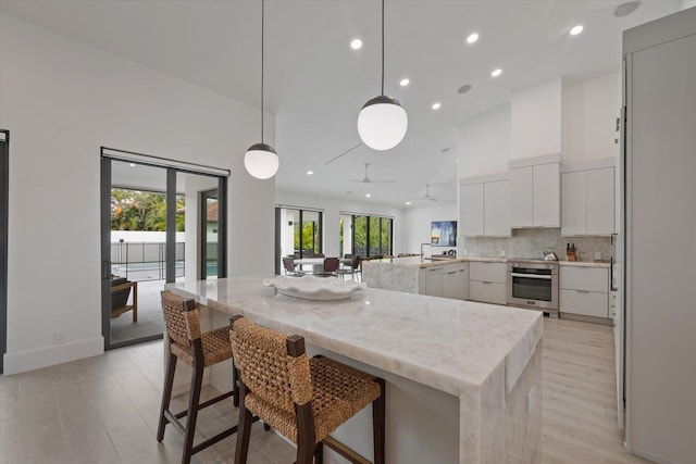 kitchen with a healthy amount of sunlight, a breakfast bar, stainless steel oven, and high vaulted ceiling