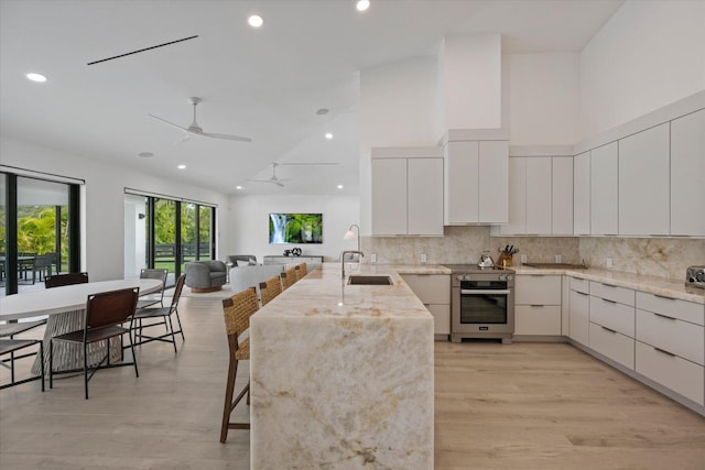 kitchen featuring light wood-type flooring, sink, stainless steel oven, kitchen peninsula, and ceiling fan