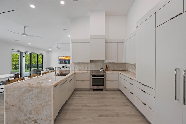 kitchen featuring light hardwood / wood-style flooring, oven, kitchen peninsula, sink, and ceiling fan