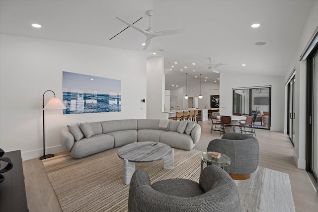 living room featuring lofted ceiling, light hardwood / wood-style flooring, and ceiling fan