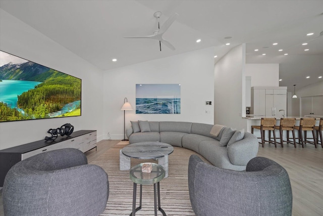 living room with lofted ceiling, ceiling fan, and light wood-type flooring