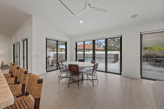 dining space featuring light wood-type flooring, high vaulted ceiling, and ceiling fan