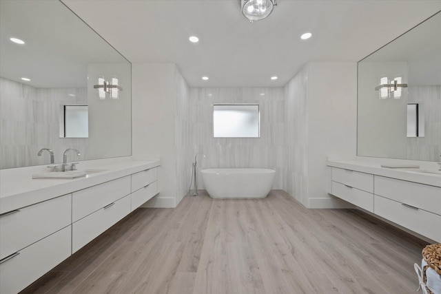 bathroom featuring vanity, tile walls, wood-type flooring, and a washtub