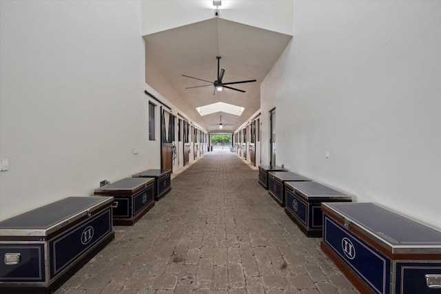 hallway with high vaulted ceiling and a skylight