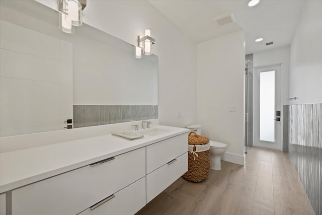 bathroom featuring toilet, hardwood / wood-style flooring, a shower with door, and vanity