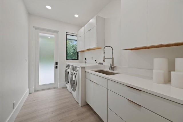 washroom featuring cabinets, washing machine and dryer, sink, and light hardwood / wood-style floors