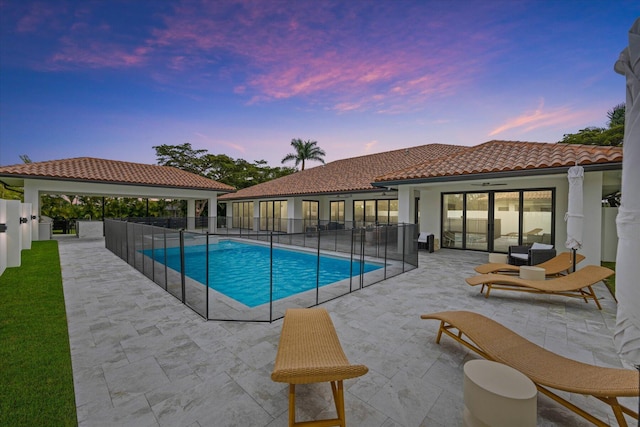 pool at dusk featuring a patio