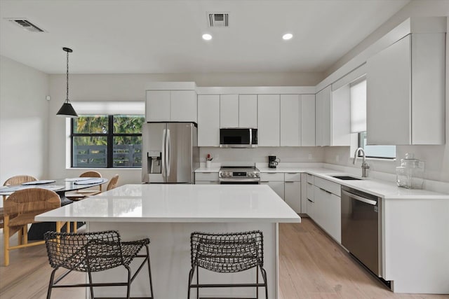 kitchen featuring light hardwood / wood-style flooring, stainless steel appliances, white cabinetry, sink, and a kitchen island