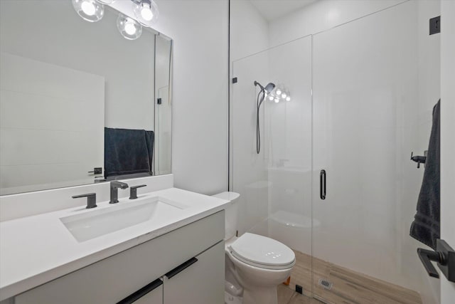 bathroom with vanity, toilet, and a shower with shower door