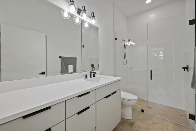 bathroom with vanity, toilet, wood-type flooring, and a shower with shower door