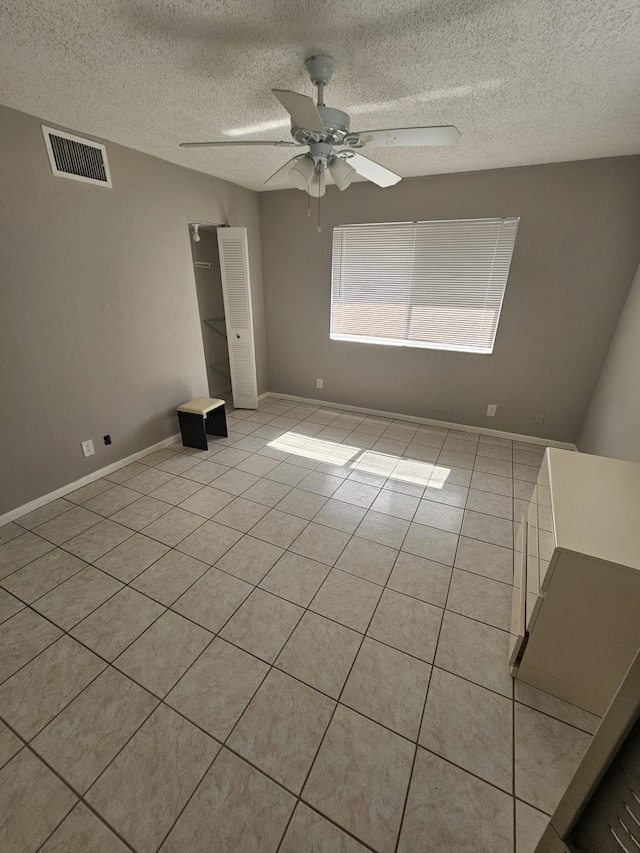 tiled spare room with ceiling fan and a textured ceiling