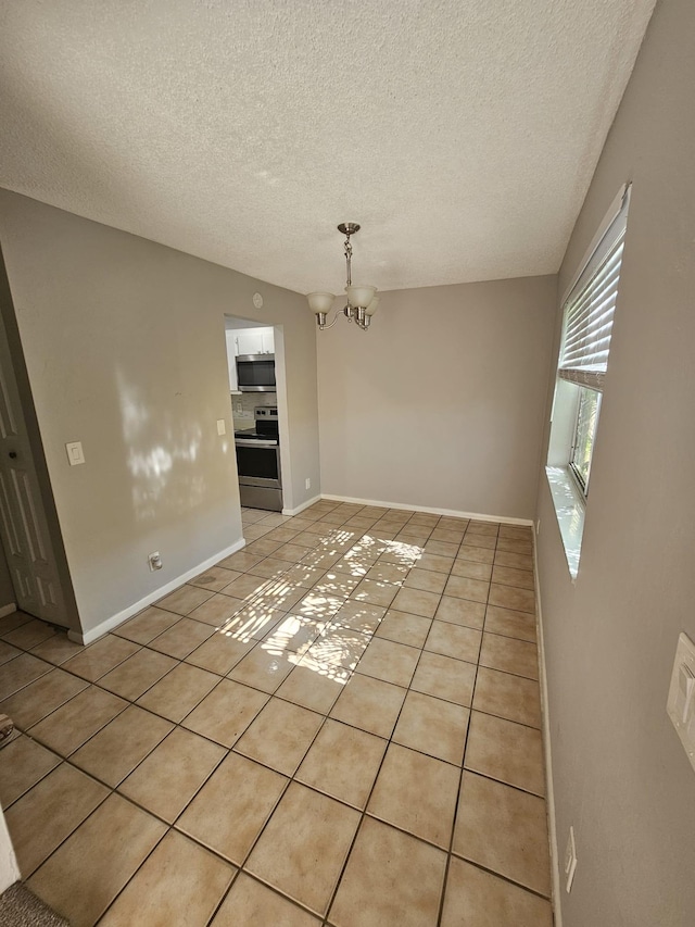 unfurnished room with light tile patterned floors, a chandelier, and a textured ceiling