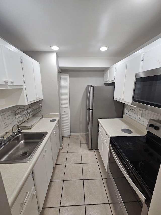 kitchen with white cabinetry, backsplash, light tile patterned floors, sink, and appliances with stainless steel finishes