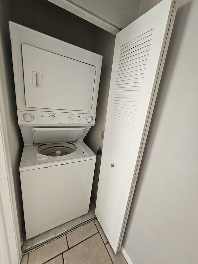 clothes washing area with light tile patterned floors and stacked washer / drying machine