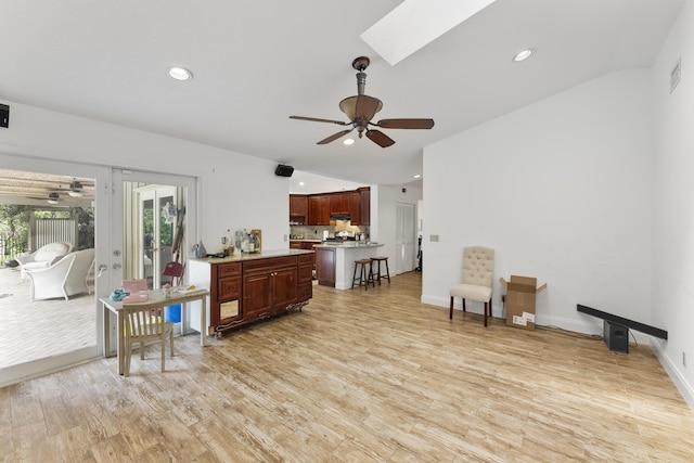 living area with ceiling fan, light hardwood / wood-style floors, and a skylight