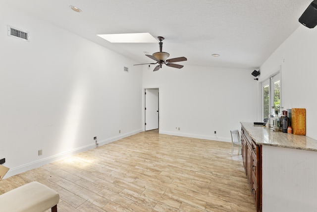 living room with ceiling fan and lofted ceiling with skylight