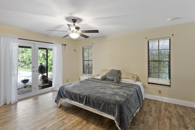 bedroom with access to exterior, ceiling fan, wood-type flooring, and a textured ceiling