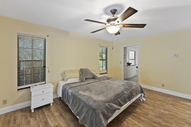 bedroom with ceiling fan, dark wood-type flooring, and ensuite bath