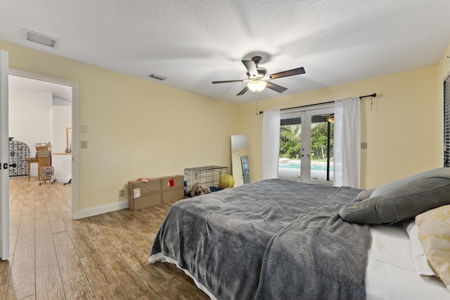 bedroom featuring ceiling fan, light hardwood / wood-style floors, access to exterior, and a textured ceiling