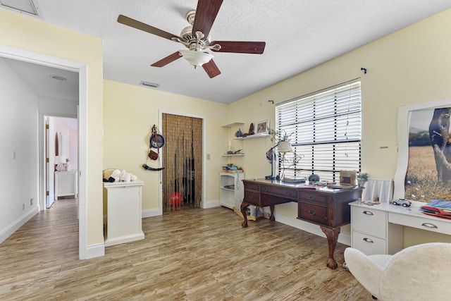 office with ceiling fan, light hardwood / wood-style floors, and a textured ceiling