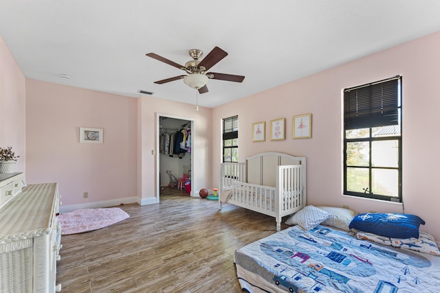 bedroom featuring ceiling fan, wood-type flooring, a walk in closet, and a closet