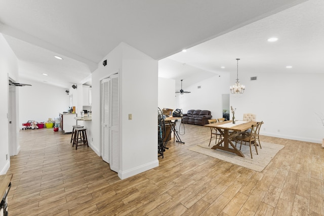 dining area featuring ceiling fan with notable chandelier and vaulted ceiling