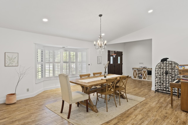 dining space featuring a chandelier, light wood-type flooring, and lofted ceiling