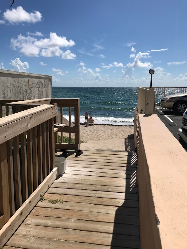 view of dock with a beach view and a water view