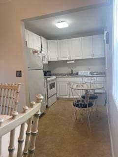 kitchen featuring white cabinetry, white appliances, and sink