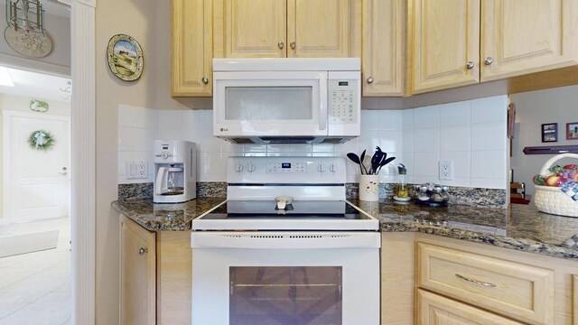 kitchen with dark stone countertops, light brown cabinetry, white appliances, and decorative backsplash