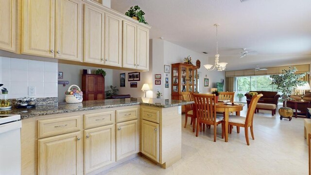 kitchen featuring hanging light fixtures, kitchen peninsula, dark stone counters, ceiling fan with notable chandelier, and backsplash