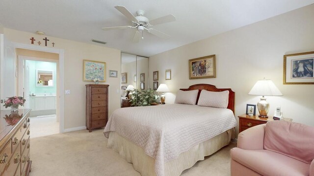 bedroom featuring ensuite bath, light carpet, ceiling fan, and a closet