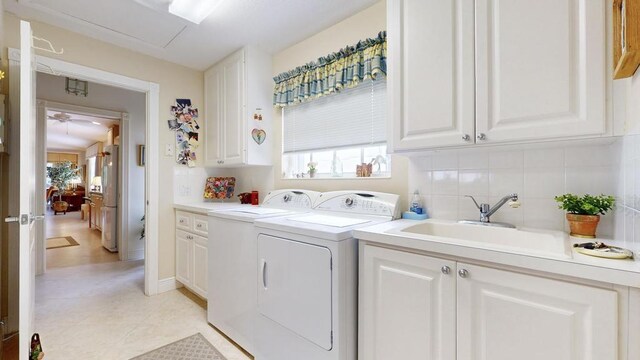 clothes washing area featuring cabinets, sink, and washing machine and dryer