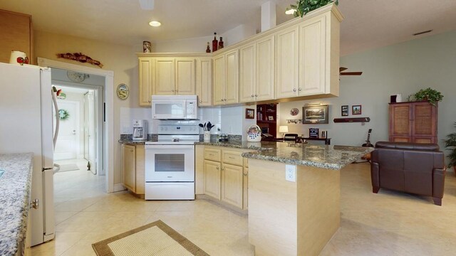 kitchen with light tile patterned flooring, white appliances, stone countertops, and kitchen peninsula