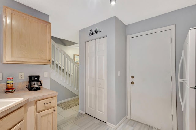 kitchen featuring white refrigerator and light brown cabinets