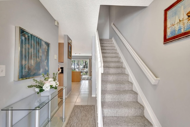 stairway with tile patterned floors and a textured ceiling