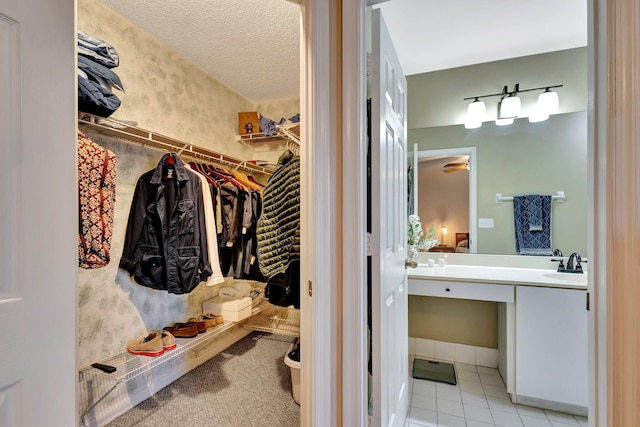 walk in closet featuring ceiling fan, light tile patterned floors, and sink