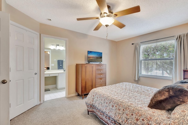 bedroom with ceiling fan, light carpet, a textured ceiling, and ensuite bathroom