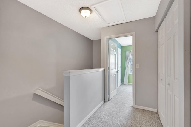 hallway featuring a textured ceiling and light colored carpet