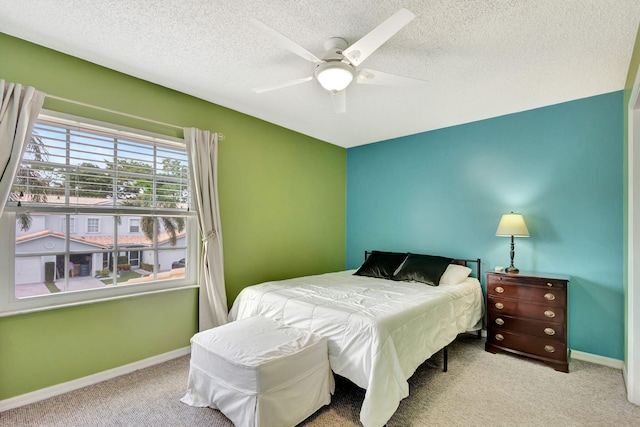 bedroom with ceiling fan, carpet floors, and a textured ceiling