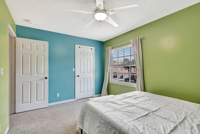 bedroom featuring light carpet, ceiling fan, and a textured ceiling