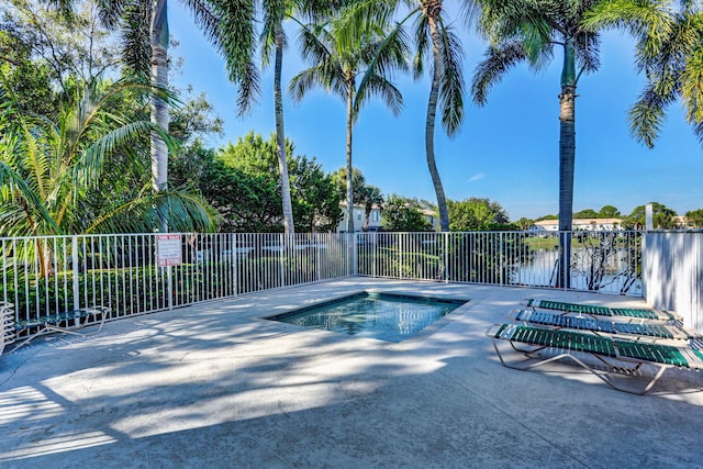 view of pool featuring a hot tub, a water view, and a patio area