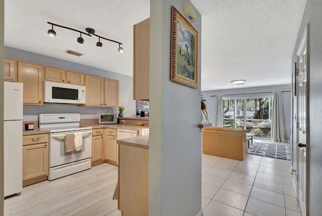 kitchen with a textured ceiling, white appliances, light brown cabinetry, and light tile patterned floors