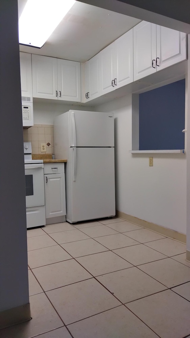 kitchen featuring white appliances, light tile patterned flooring, white cabinets, and tasteful backsplash