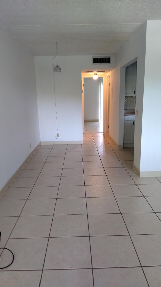 empty room featuring a textured ceiling and light tile patterned flooring