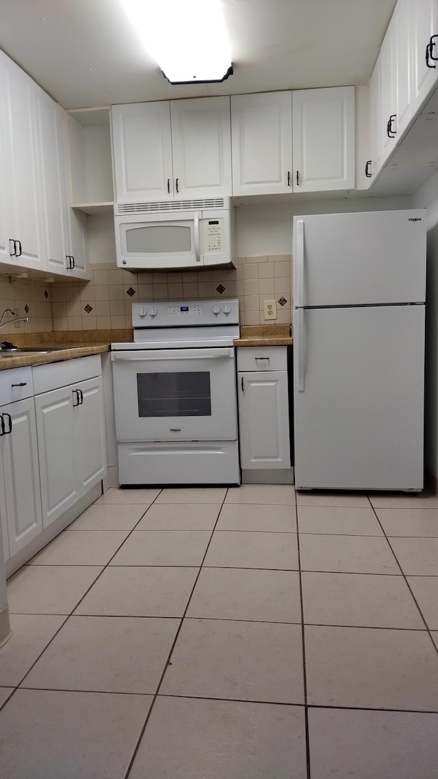 kitchen with white appliances, backsplash, white cabinetry, and light tile patterned flooring