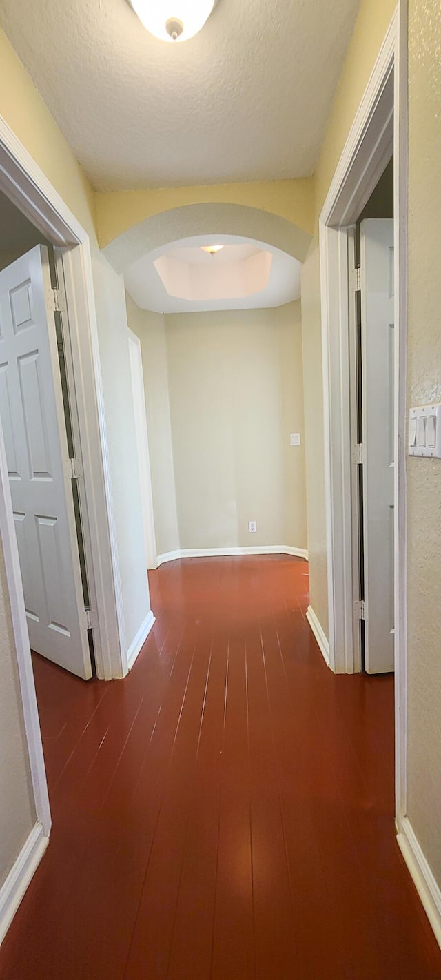 hall featuring a textured ceiling and dark hardwood / wood-style flooring